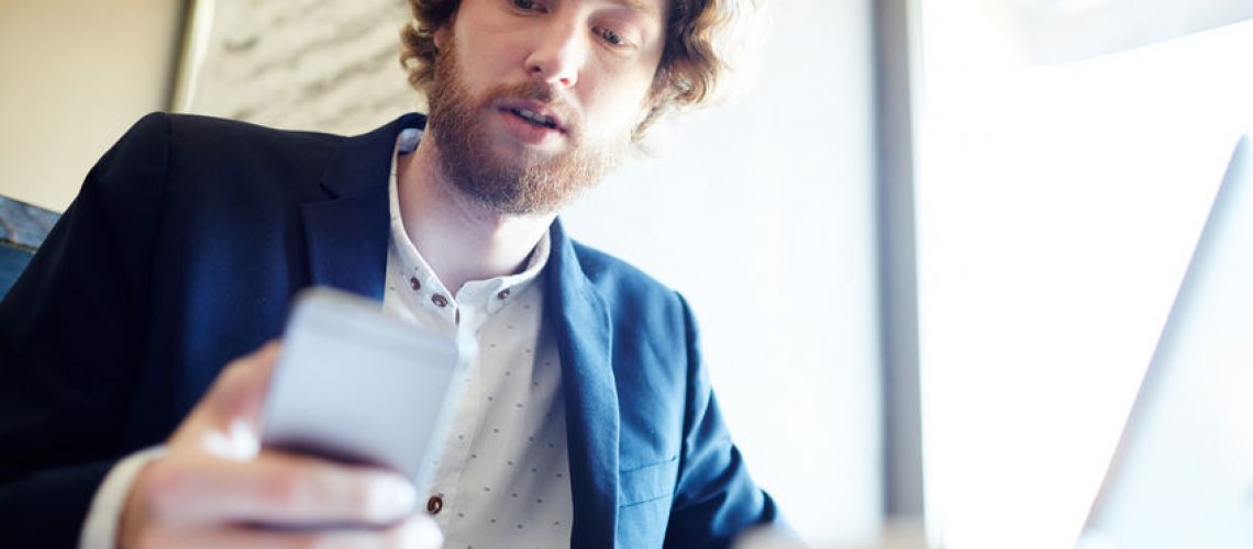 Contemporary man reading message in smartphone during work